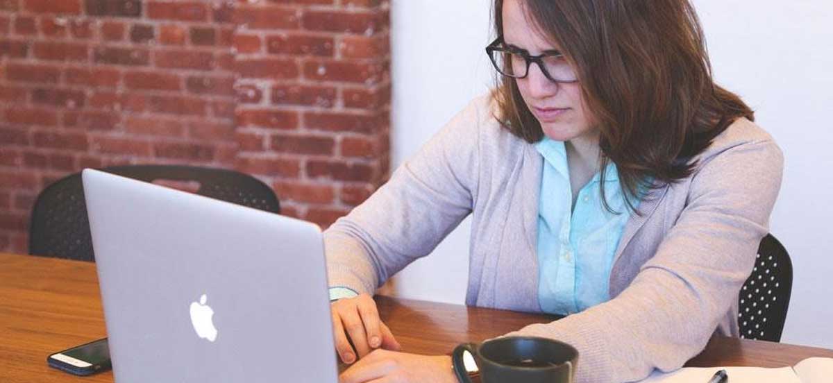 Das Bild zeigt eine junge Frau, die angestrengt in einen Monitor starrt. Es symbolisiert die Disziplin, die für eine aktuelle Website nötig ist.